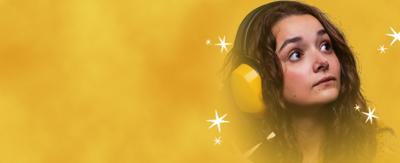 A young girl with long brown hair and wide eyes is staring into the distance. She is wearing bright yellow ear defenders and is surrounded by stars and yellow/orange clouds