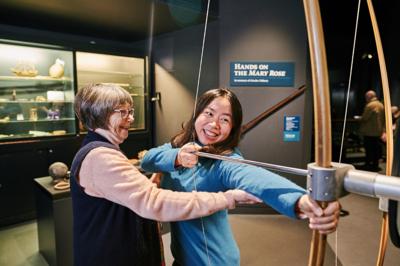 A girl uses a longbow at the Mary Rose Museum