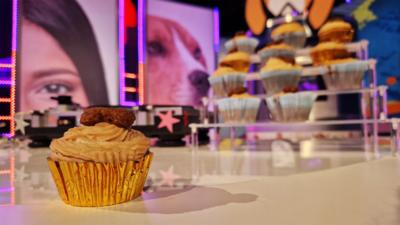 A cupcake made for dogs, it is made of banana and peanut butter and decorated with a dog treat.