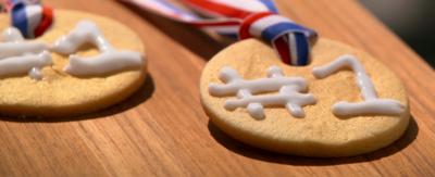 Golden biscuits shaped like medals with ribbons through the top.