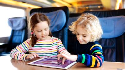 Two children on a train playing together on a tablet | CBeebies free apps for kids.