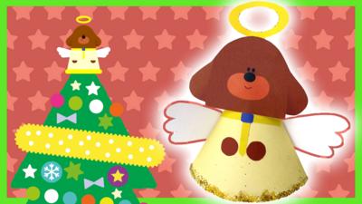 A handmade Duggee angel tree toppers is glowing next to the onscreen version sat on top of a tree.