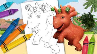 Crayons next to a paper showing line art of Vegesaurs character Ginger. Coloured in image of Ginger character is next to paper.