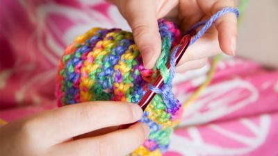 Hands crocheting a blanket