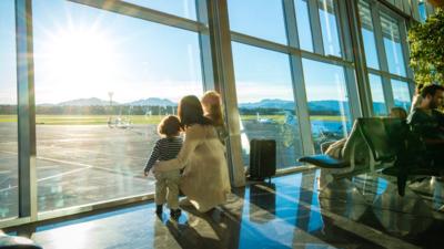 Mother and two children looking out of window at an airport.