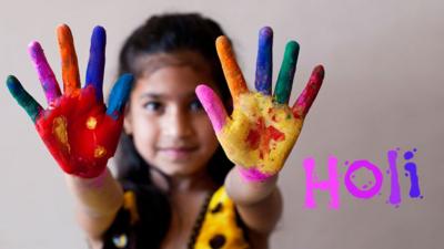 young girl with painted hands next to the word 'holi'.