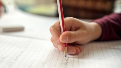 Young child's hand holding a pencil on top of paper.