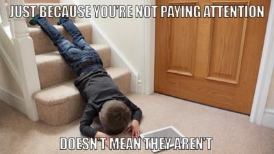 Child lying face down on stairs with iPad next to him.