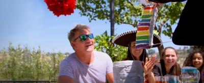 A man and a woman look amazed at a multicoloured cake.