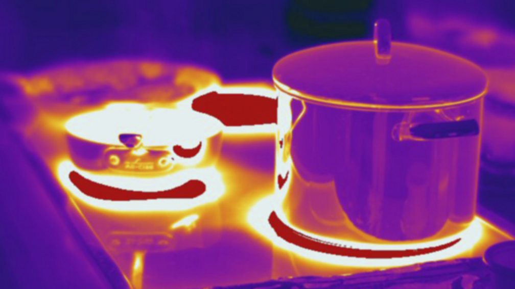 Thermogram of a pan on a stove showing the hottest parts in white, yellow or red, and the coldest parts in purple and black.