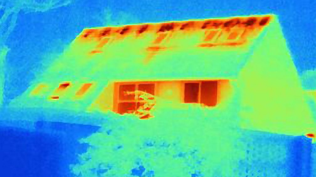 A thermogram of a house, showing areas of heat loss. The roof and the windows are the yellowest and reddest areas, indicating that most energy is lost from the house this way.