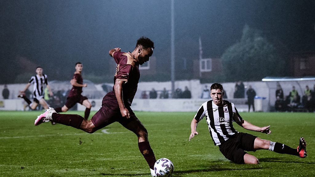 Liam MacDevitt strikes ball for Bury AFC against challenge from Walshaw Sports FC player