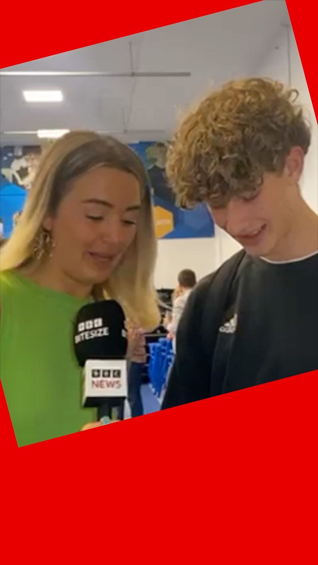 Lucy, in a green top, stands next to Ben, in a black jumper, as he opens his results