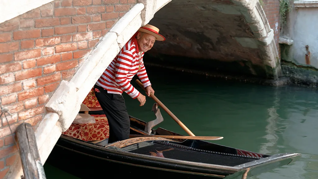Sandolista and tourists on a sandolo in a Venetian canal (Credit: Carola Cappellari)