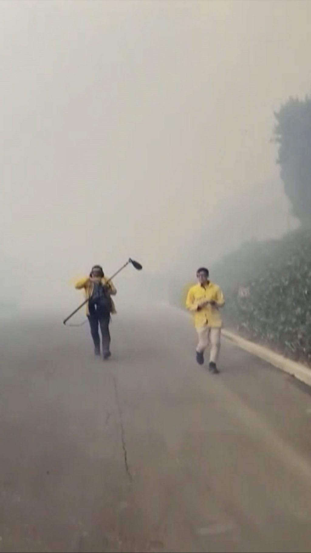 Two people running away from billowing smoke