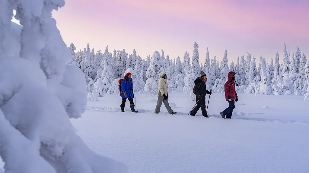 Four travelers hike through the snow in Finland. (Credit: Getty Images)