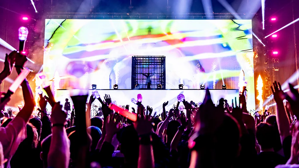 A still from an Ado gig showing a crowd of fans with their hands in the air