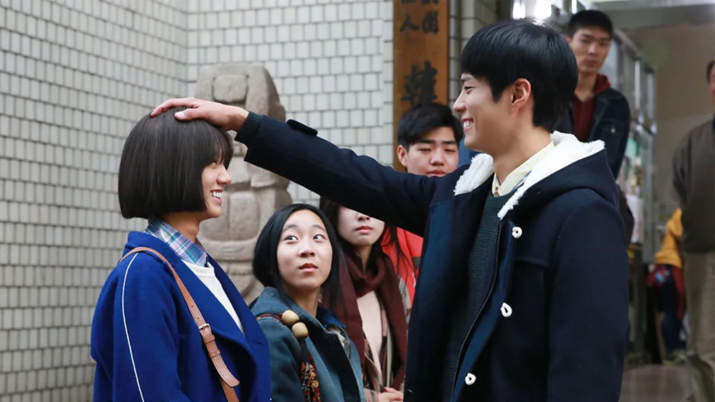 A still from Reply 1988, showing one character resting his hand on the head of the other