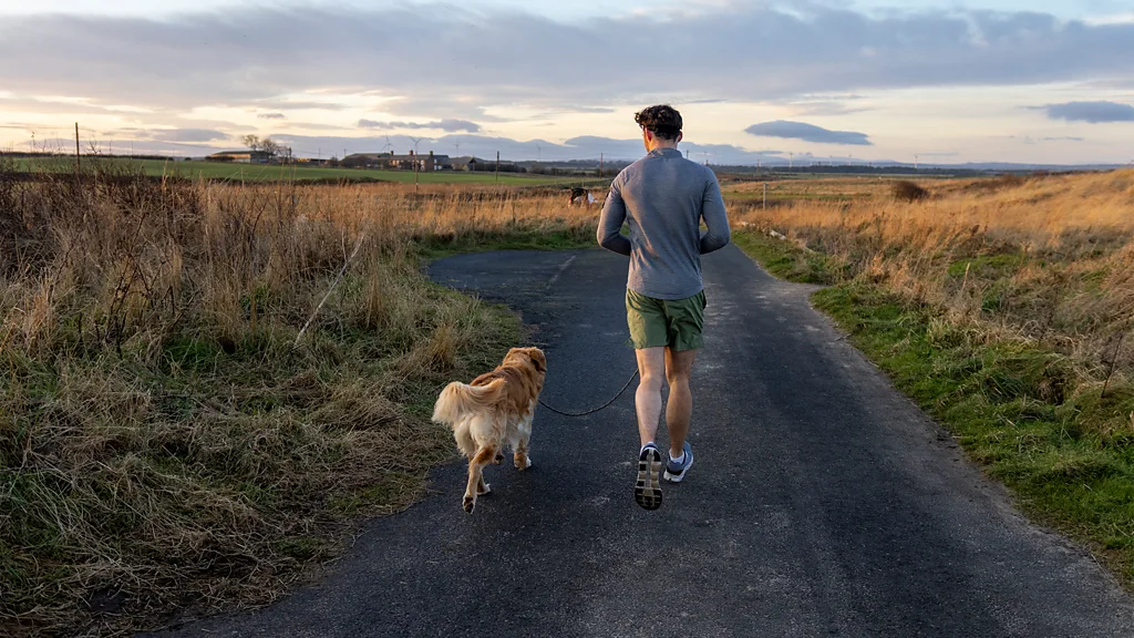 A man running on a countryside with his dog (Credit: Getty Images)