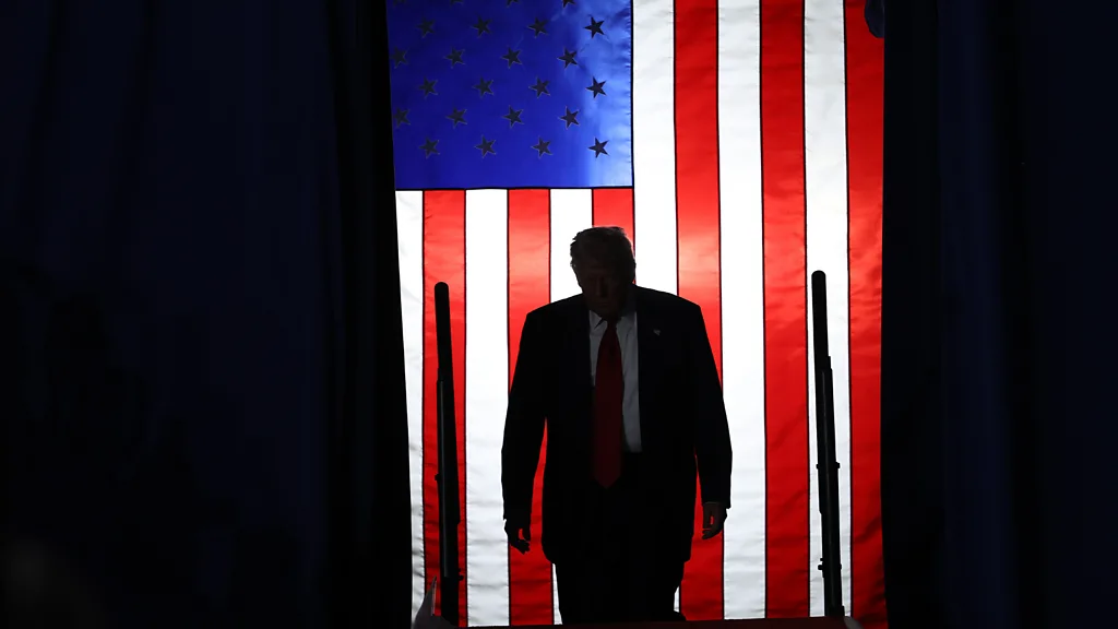 A silhouette of President Donald Trump with an American flag hanging behind him (Credit: Getty Images)