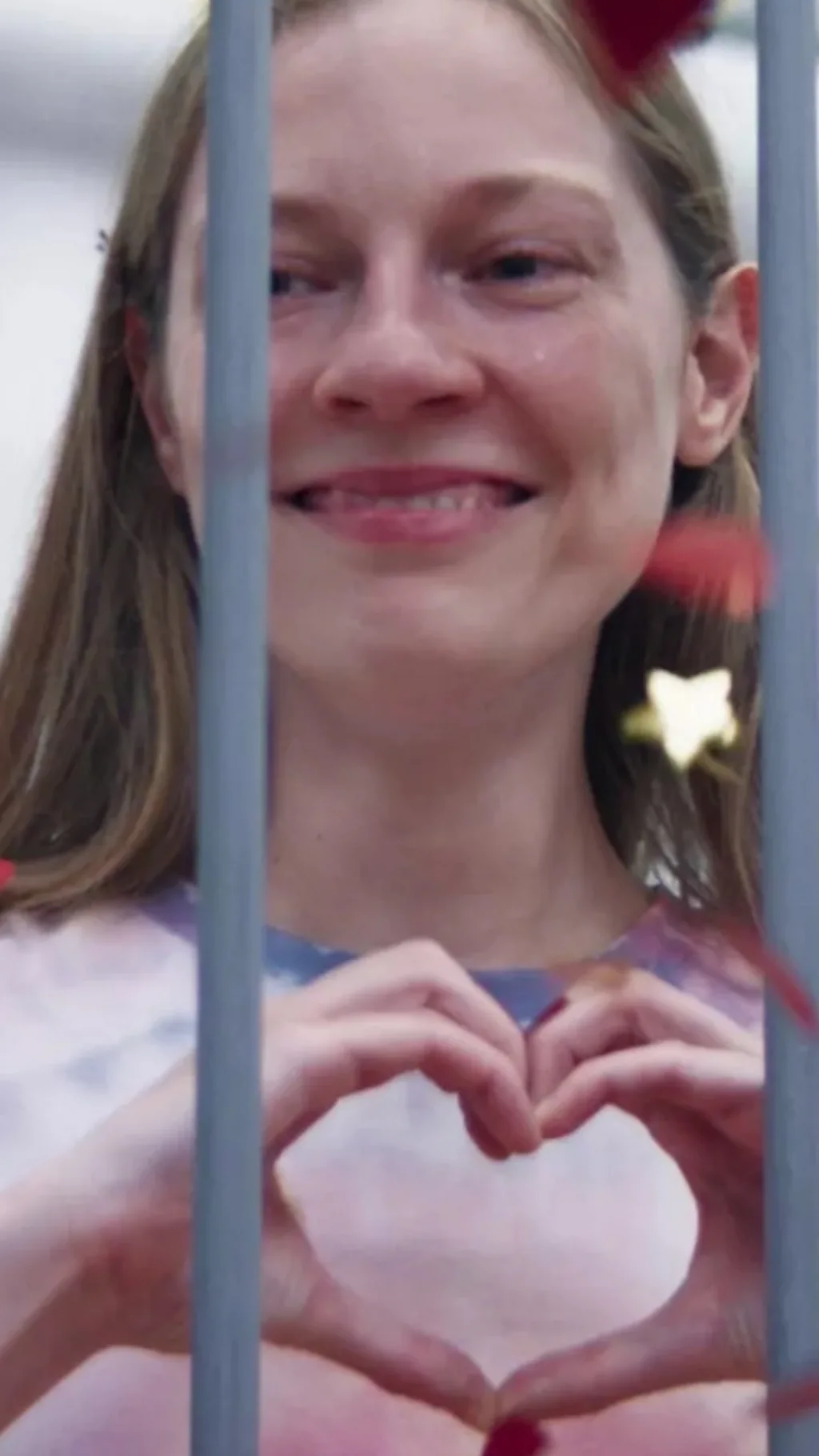 девушка за решеткой сложила руки в форме сердца