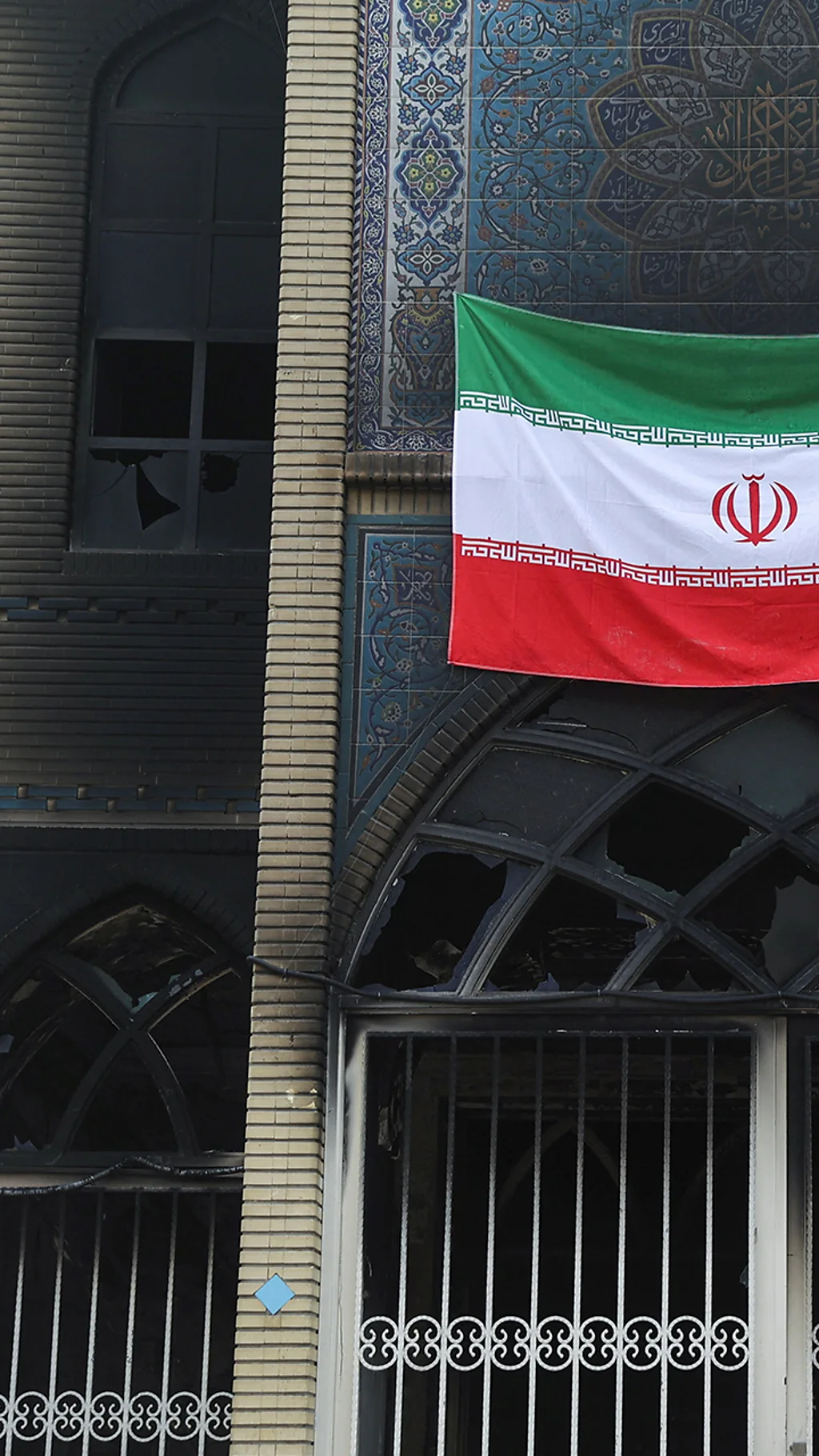 Сожженное здание в Тегеране с иранским флагом.