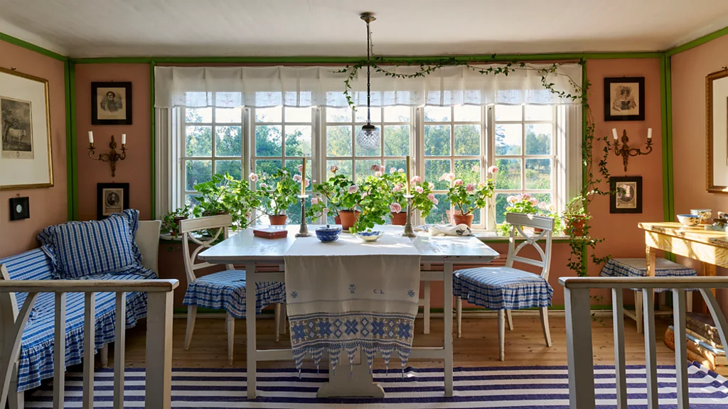View of a dining table in front of a window with pink roses on the windowsill (Credit: Richard Powers/ The Iconic Nordic House)