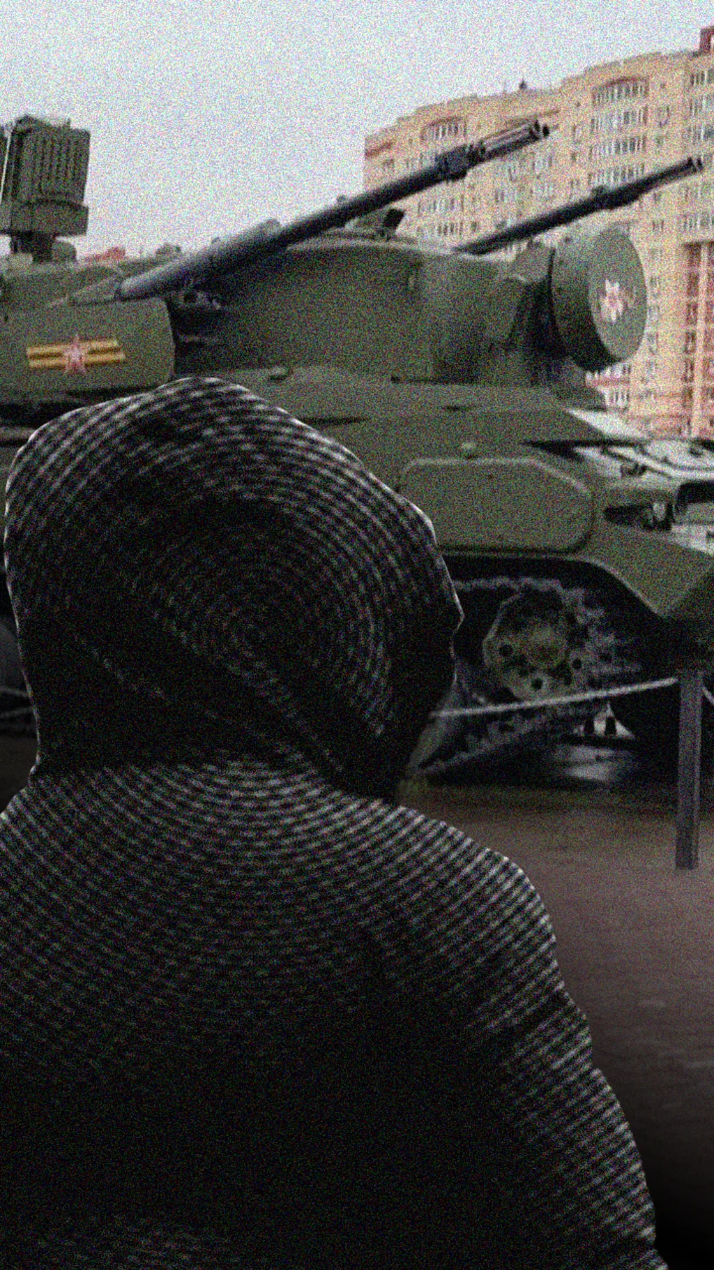 Человек в капюшоне на фоне танка.