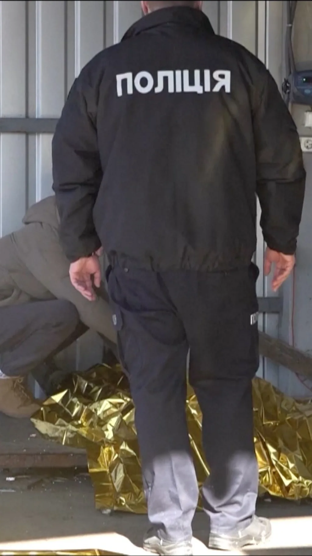 полицейский стоит рядом с телом погибшего