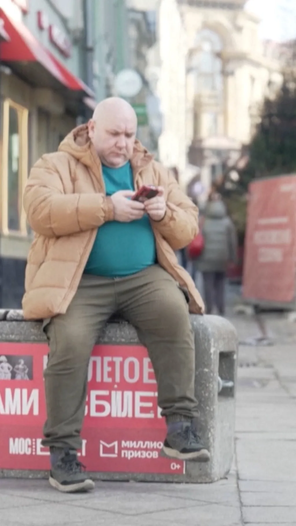 мужчина сидит на лавке и смотрит в телефон