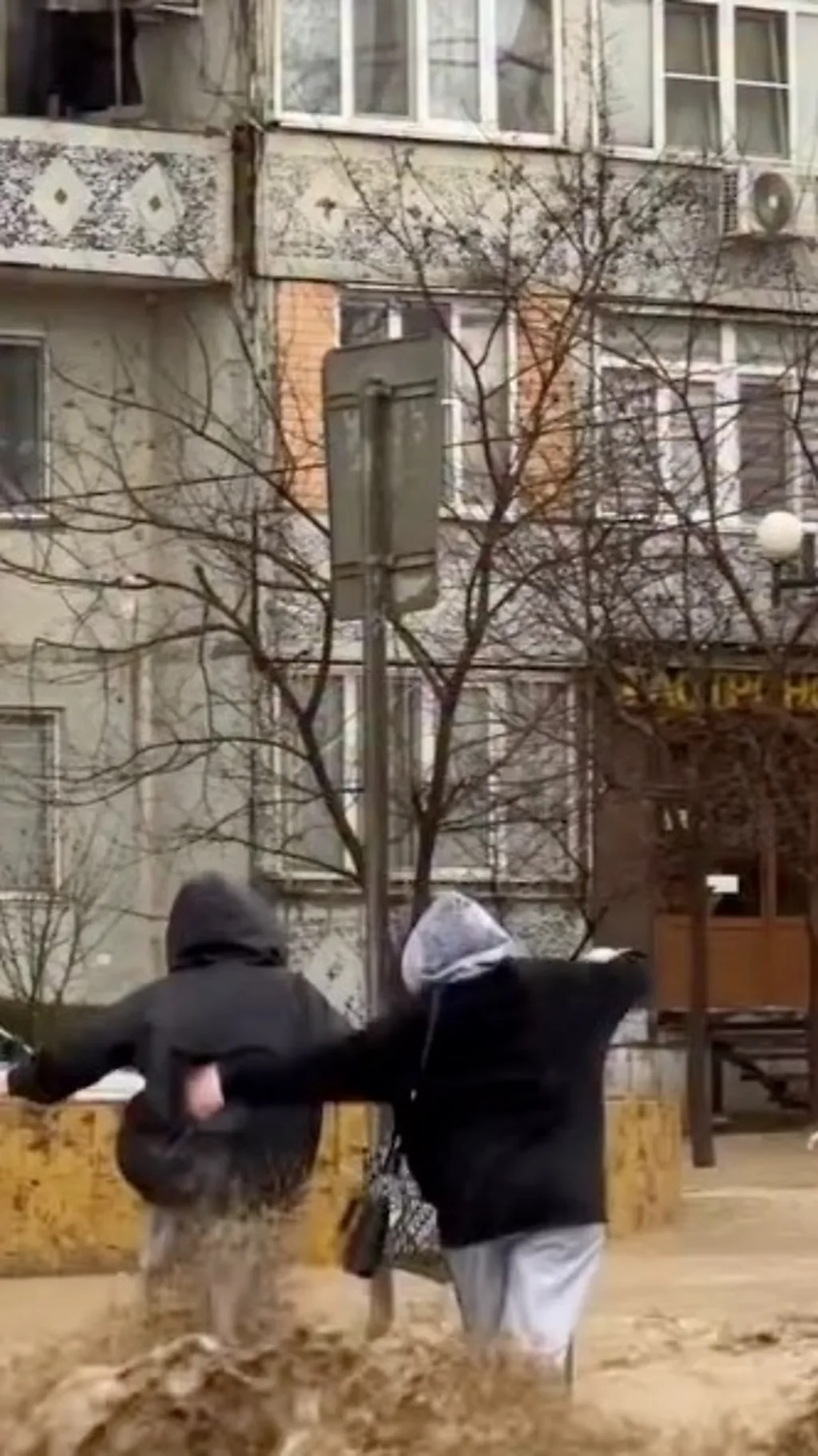 Девушки переходят залитую водой дорогу