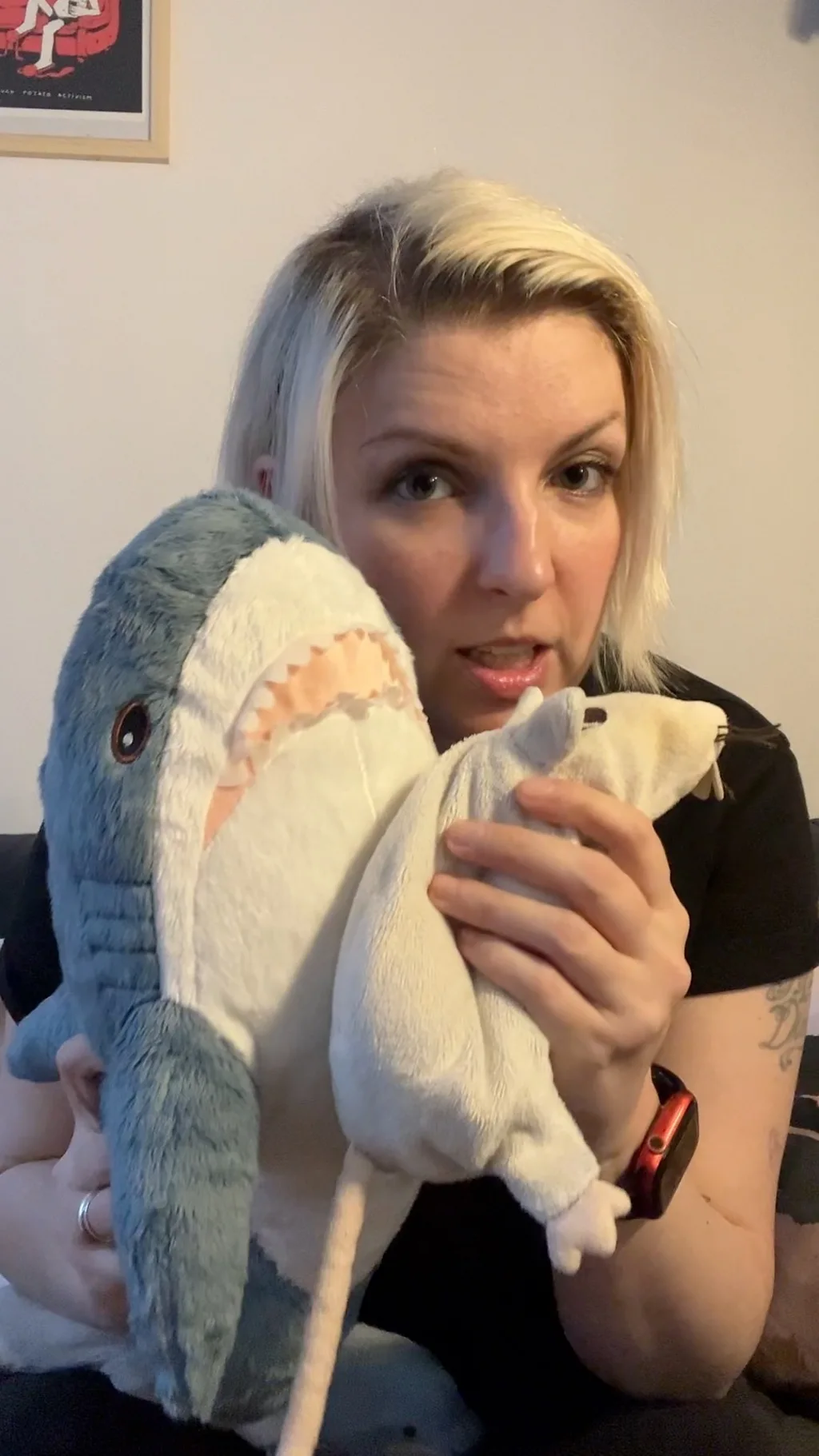 novinarka drzi plisanu ajkulu i pacova igracke