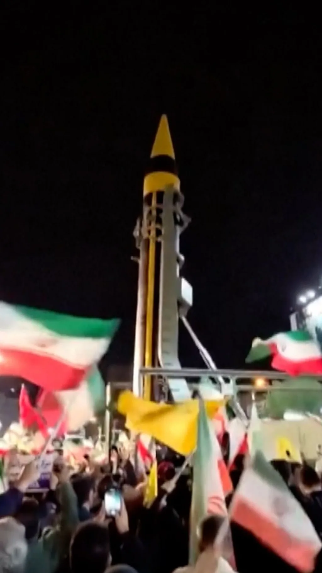 ईरान की राजधानी तेहरान में मिसाइलों के पास जुटे लोगों ने लहराए ईरानी झंडे