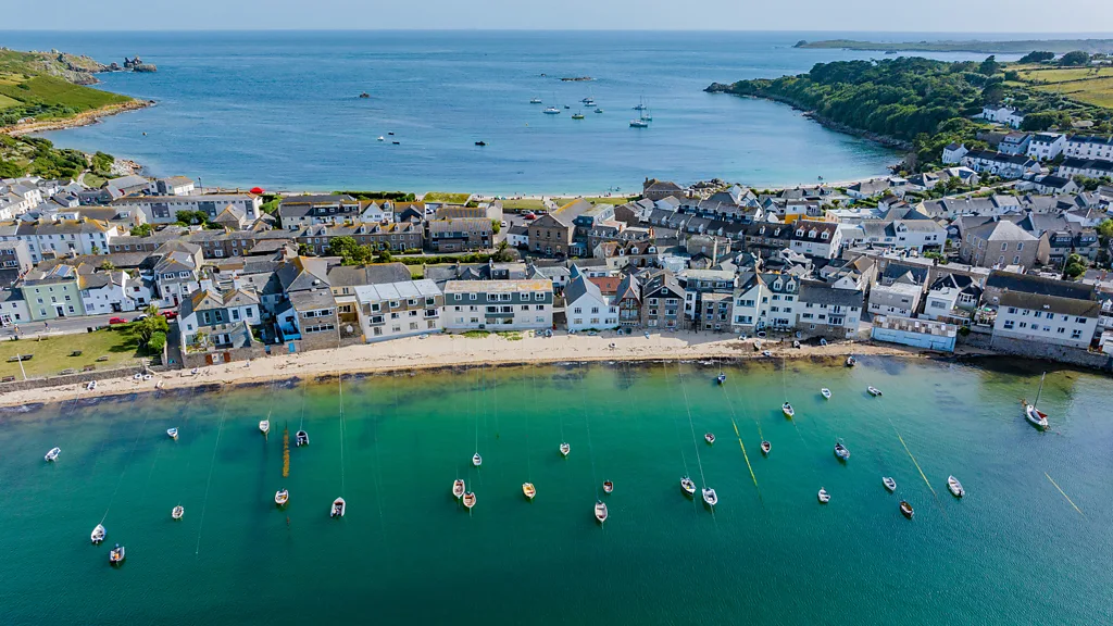 Aerial view of small harbour village in England with fishing boats moored between breakwaters (Credit: Getty Images)