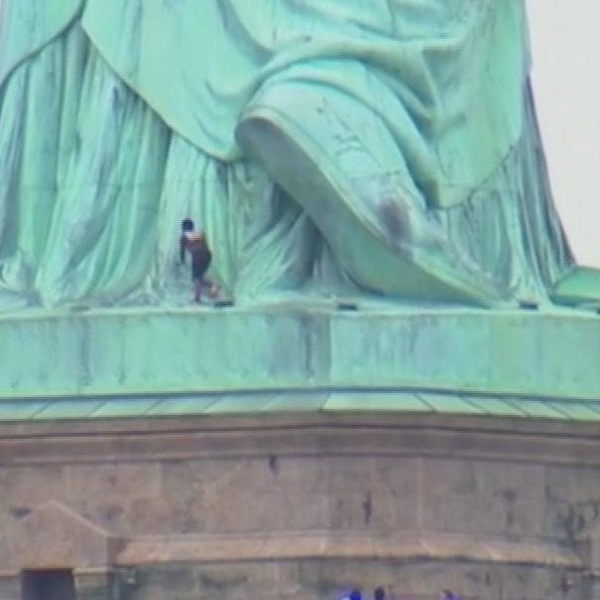 Person climbs to Statue of Liberty base