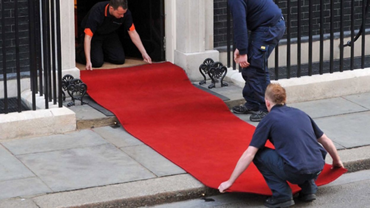 Man fixing red carpet in an event in Oshawa
