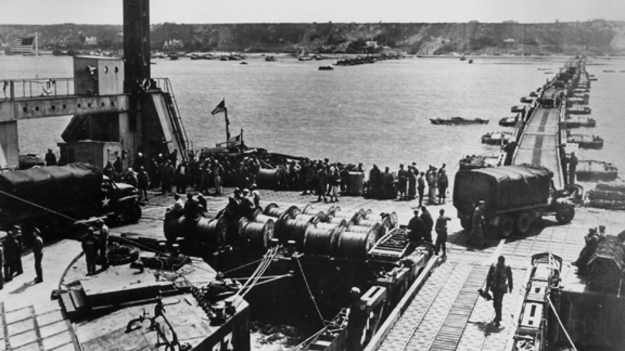 A photograph of a harbour, with military supplies being arranged.