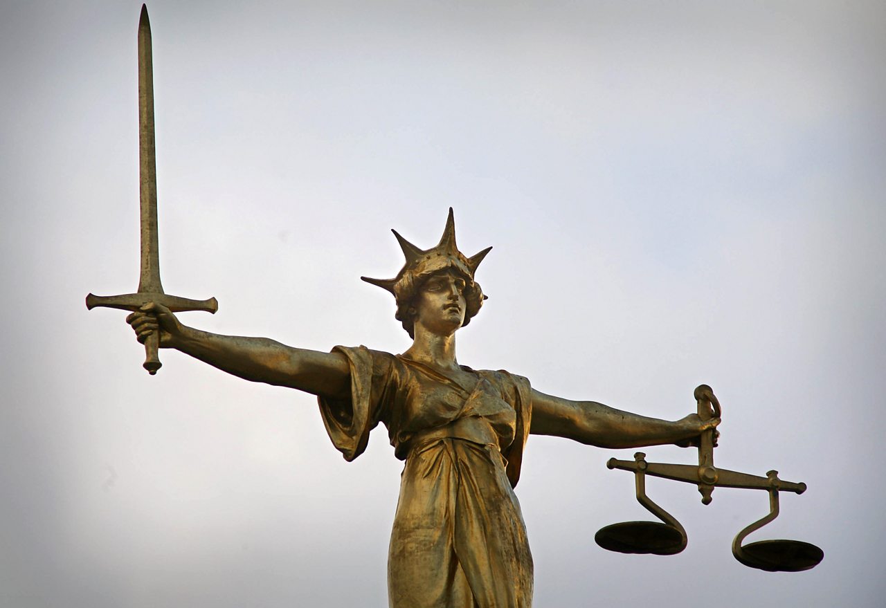 A statue with a figure holding a sword and a set of scales, representing justice.