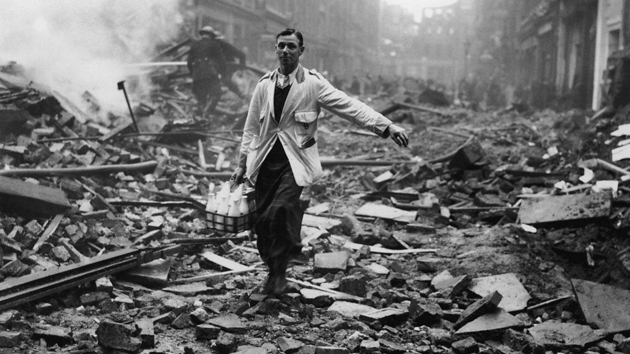 A milkman delivering milk in a London street devastated during a German bombing raid.
