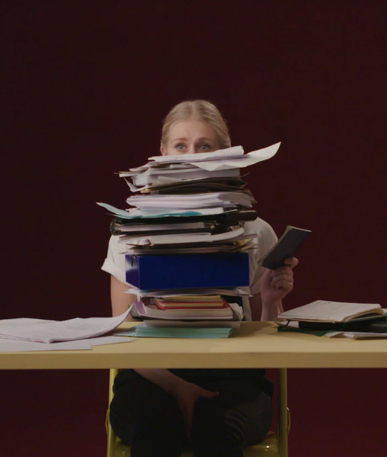 Files stacked with a girl peering over the top