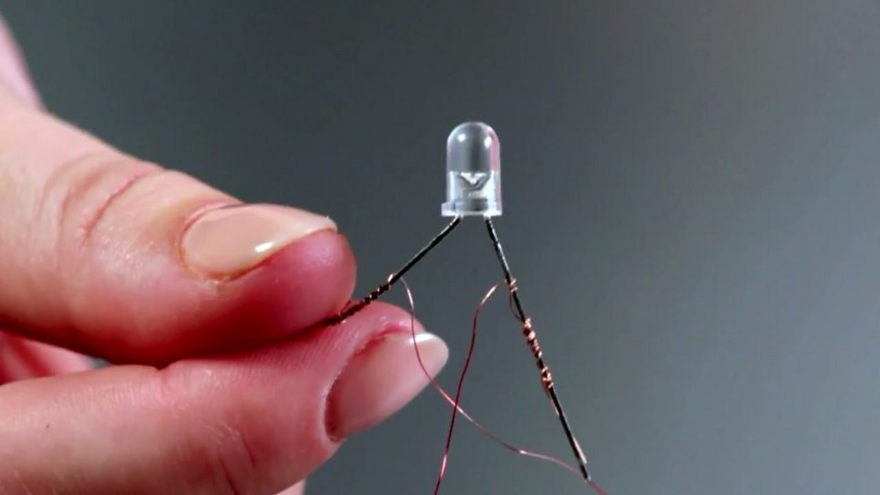 An LED bulb and the leg of the bulb being wrapped around the copper wire