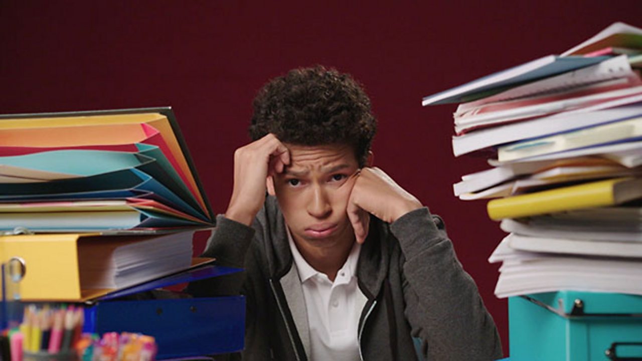 Boy looking sad with two piles of revision notes around him.