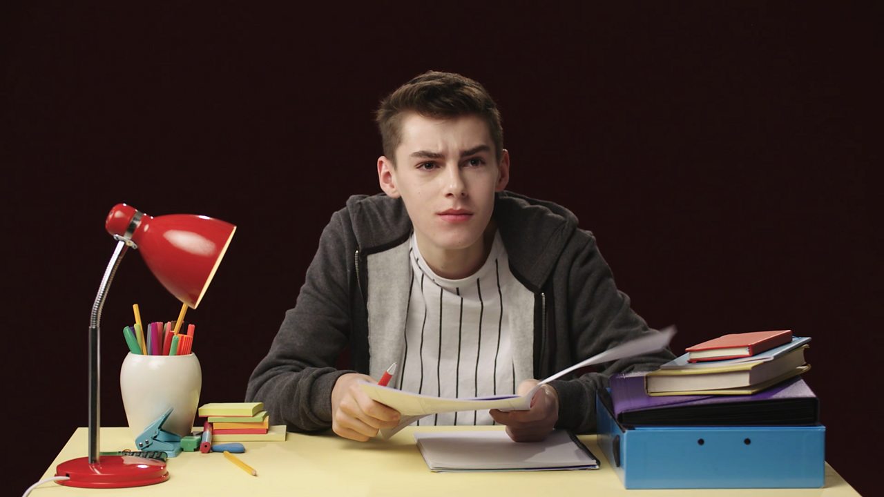 Boy looking into the camera holding up a past paper.