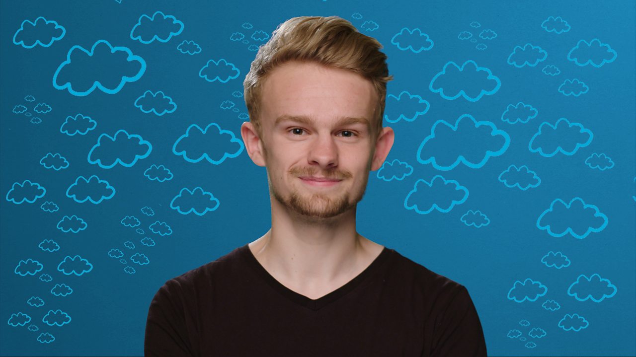A young man sits looking directly at the camera