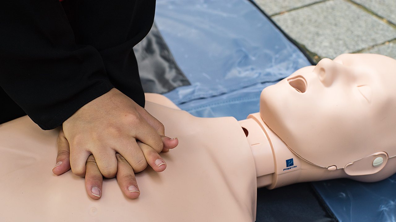 A young woman, Khadija, performing a heart massage on a CPR dummy