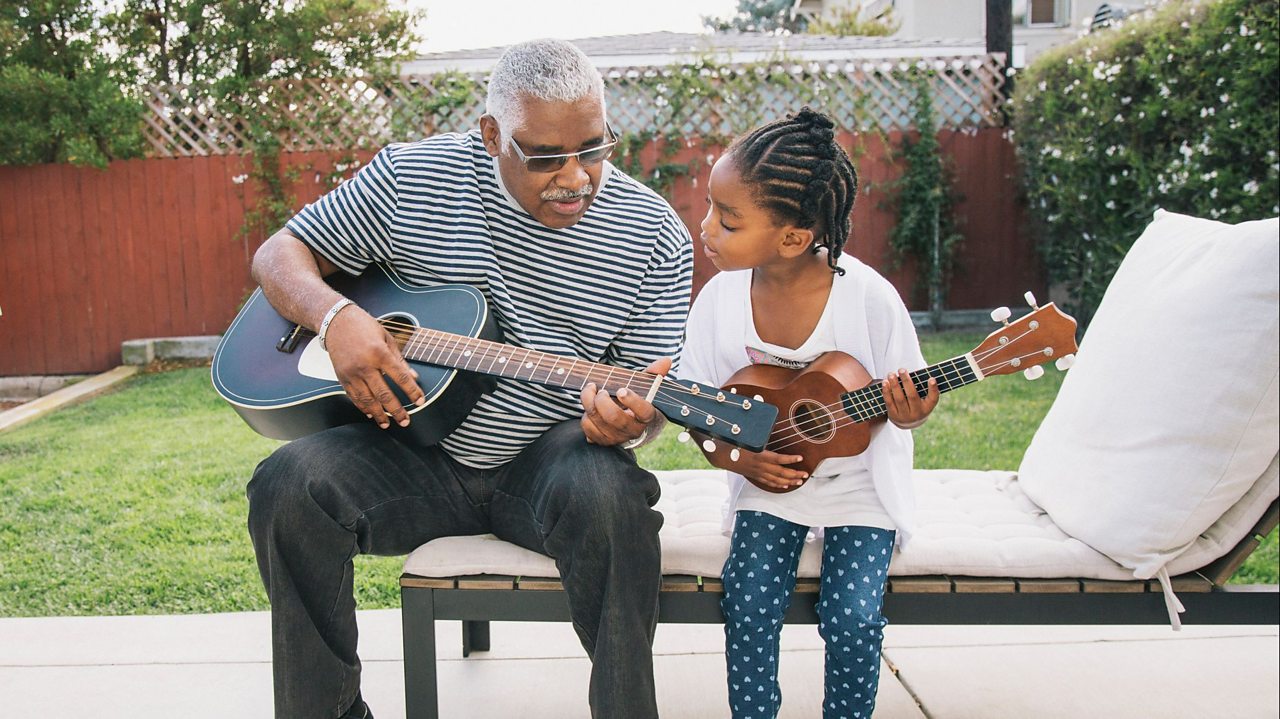 A grandpa teaching his granddaughter how to play the ukulele