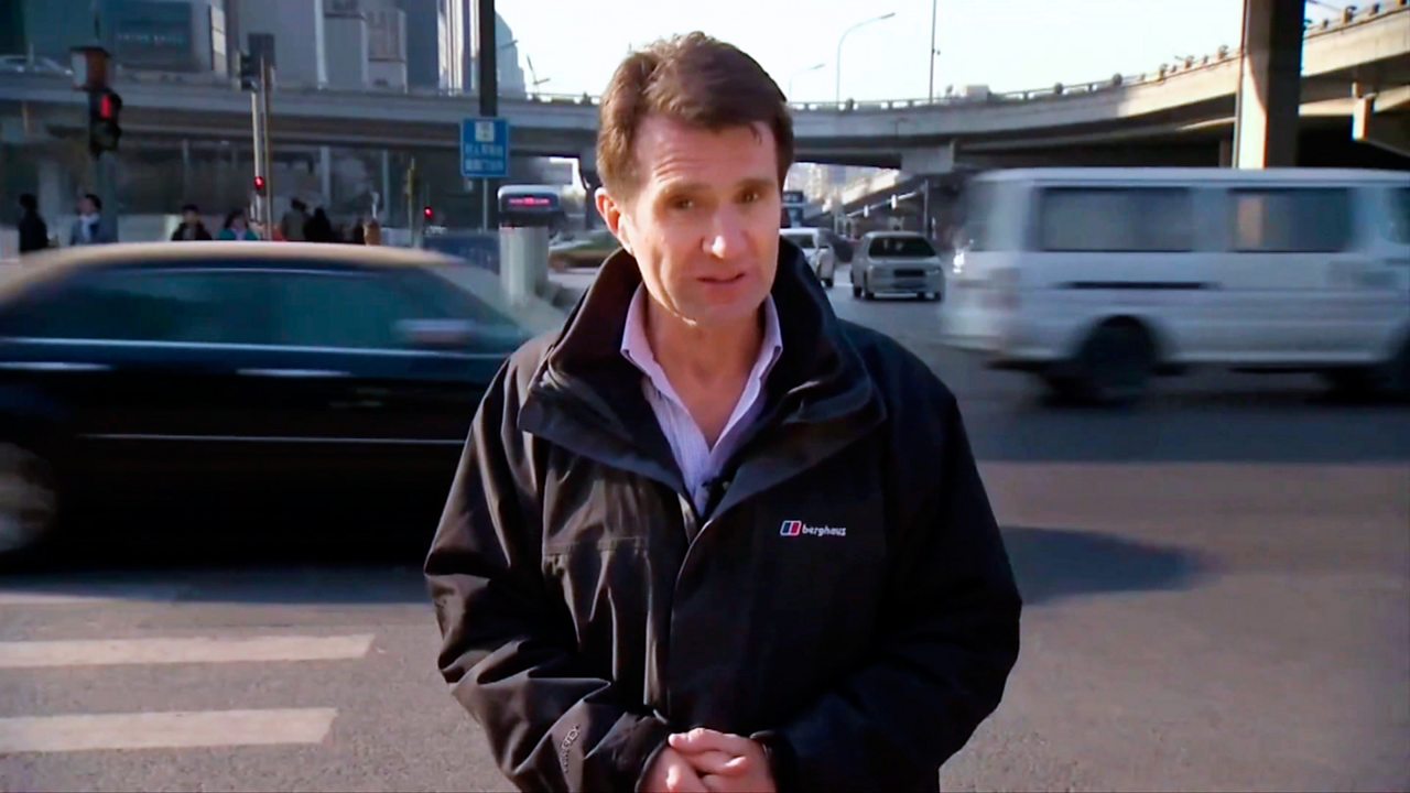 David Shukman, Science Editor, BBC News, standing in front of a road.