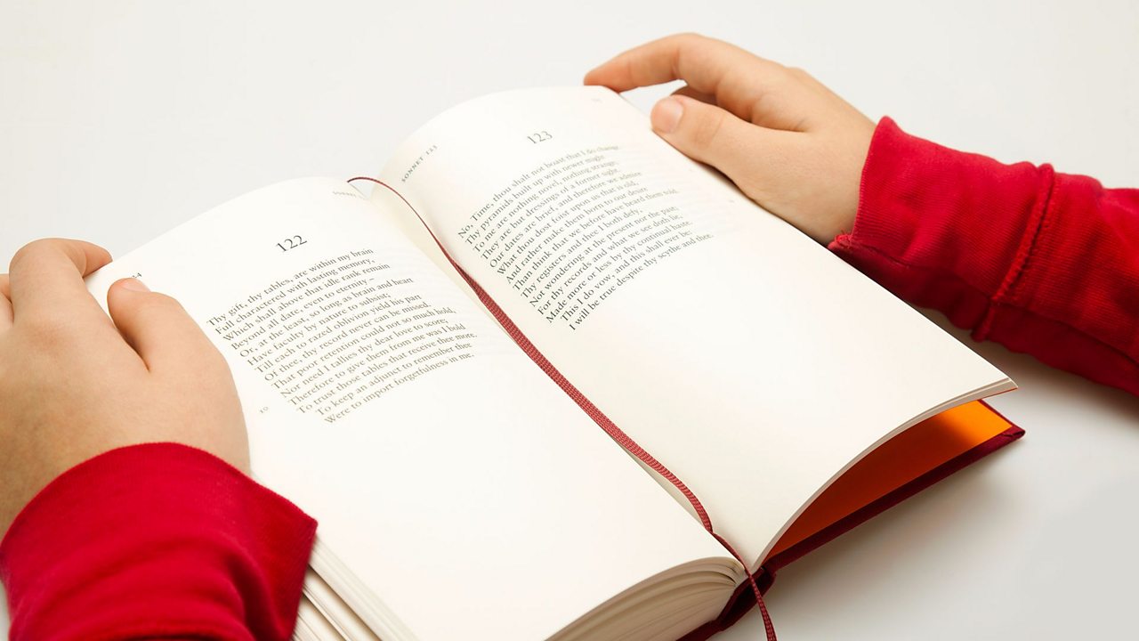 Hands hold open a book of Shakespeare's sonnets showing 14 lines per sonnet