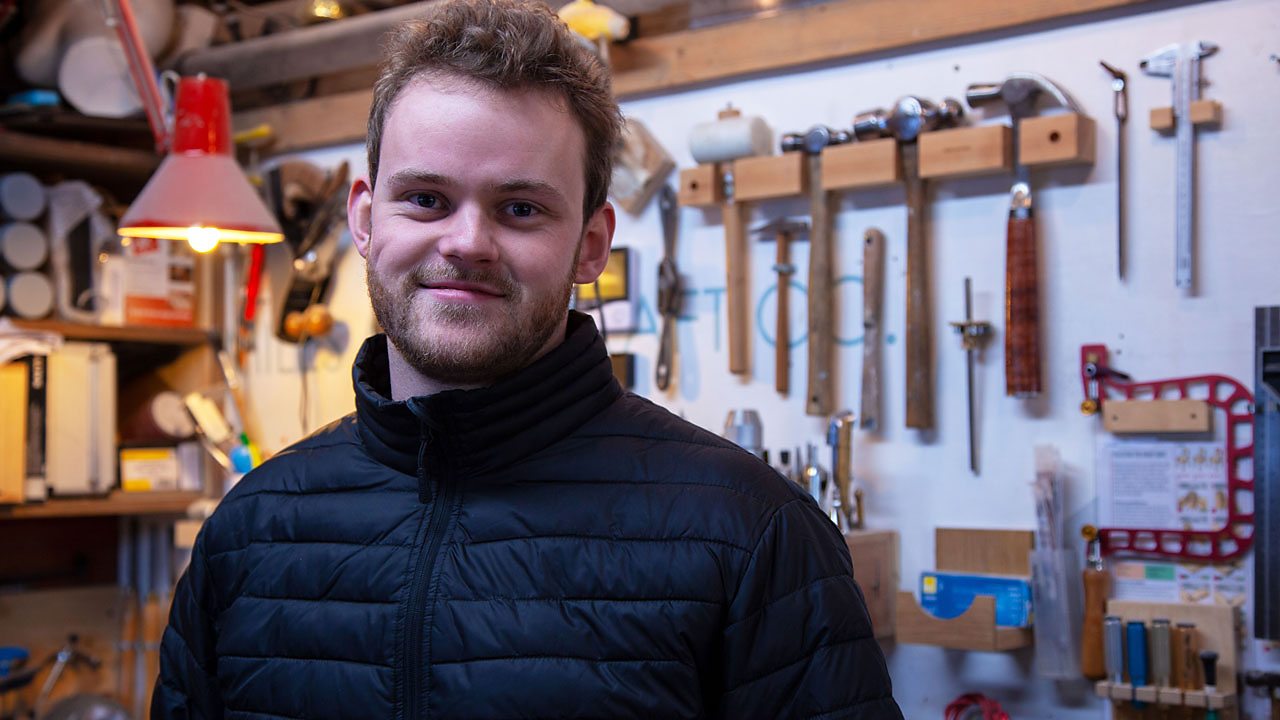 Miles in his workshop, smiling at the camera.