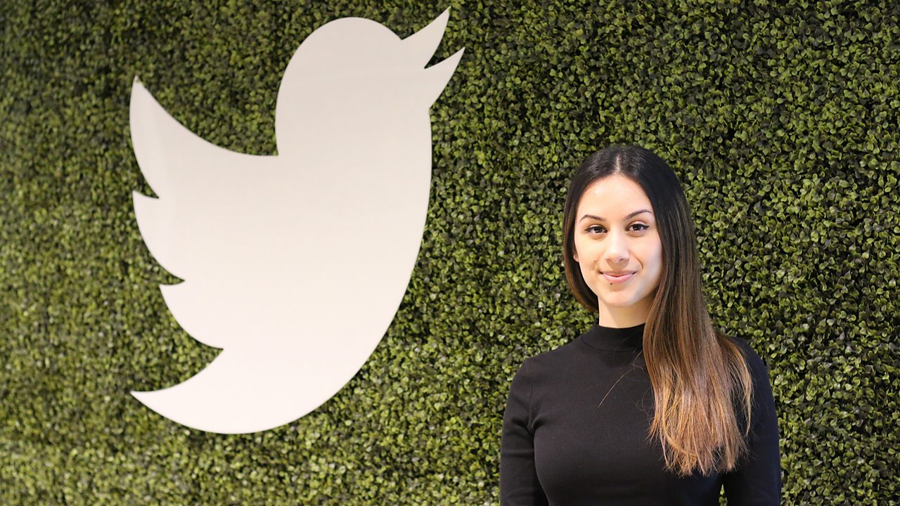 Melina standing next to the Twitter logo at work.